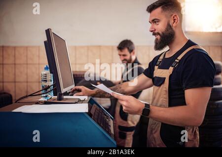 Al servizio auto.Due meccanici automatici che eseguono la diagnostica con computer .Servizio auto, riparazione e concetto persone. Foto Stock