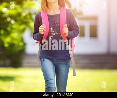 Ragazza con zaino infront di un edificio scolastico Foto Stock