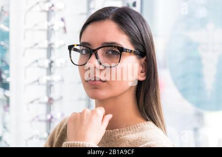 primo piano ritratto di una bella donna scegliere occhiali. giovane con scarsa vista Foto Stock