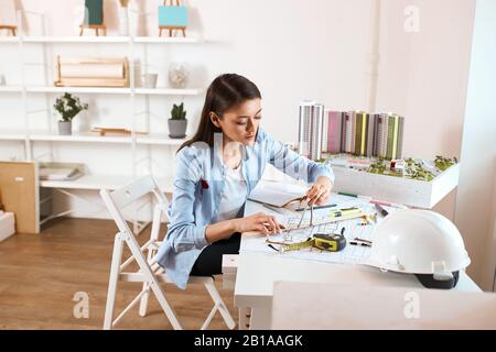 giovane talento achitect usando le bussole mentre disegna un modello di costruzione, primo piano foto. lavoro, professione occupazione. ragazza alla ricerca di nuove idee per co Foto Stock