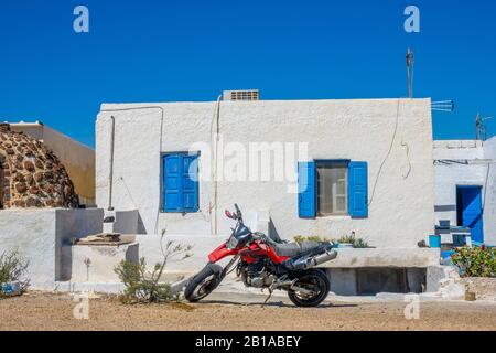 Grecia. Città di Oia sull'isola di Santorini. Moto rosso di fronte ad una casa locale Foto Stock