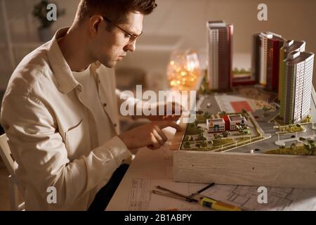 Tecnologia , giovane uomo che lavora con un layout del futuro edificio. Primo piano vista laterale foto. Foto Stock