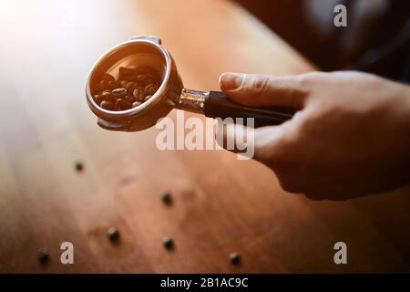 uomo che tiene il portafiltro con chicchi di caffè, primo piano foto ritagliata Foto Stock