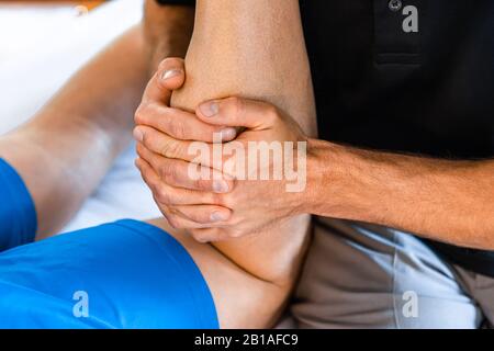 Un massaggiatore sportivo professionale irriconoscibile che lavora su gambe di sportivo dopo la lesione. Osteopatia e concetti di riabilitazione delle lesioni sportive Foto Stock