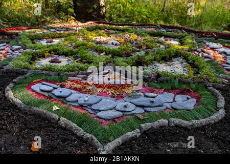 Un modello circolare è visto su un pavimento di foresta. Bella opera d'arte fatta di flora naturale e oggetti trovati nel bosco durante il festival della terra con spazio copia Foto Stock