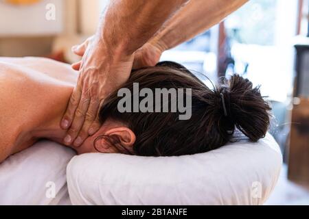 Terapista professionale che offre un delicato massaggio al collo alla donna. Vista ravvicinata del massaggio corpo in corso. Donna che riceve il massaggio del collo nel centro termale Foto Stock