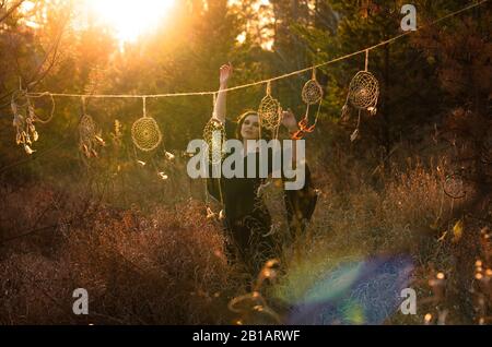 Donna boho con capelli ventosi corti. Silhouette femminile con catcher da sogno attraverso i raggi del sole Foto Stock