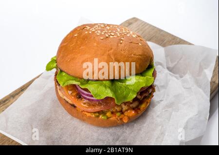 Hamburger fatto in casa con lattuga, pomodoro, formaggio e cetrioli su una tavola di legno Foto Stock