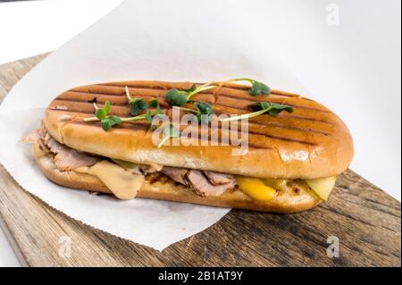 Tagliare il formaggio e il prosciutto cotto panini fuso. Panino grigliato servito su una tavola di legno Foto Stock