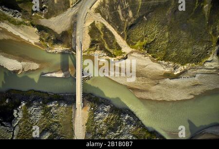 Dall'alto, vista dei droni sul moderno ponte che attraversa il tranquillo fiume sporco e collega le strade negli altopiani islandesi Foto Stock