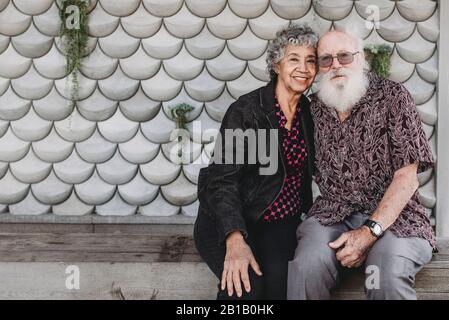 Ritratto di coppia anziana attiva seduta e sorridente fuori Foto Stock