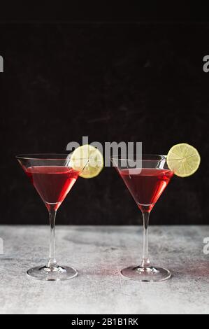 Due martini cosmopoliti su un banco grigio con sfondo nero. Foto Stock