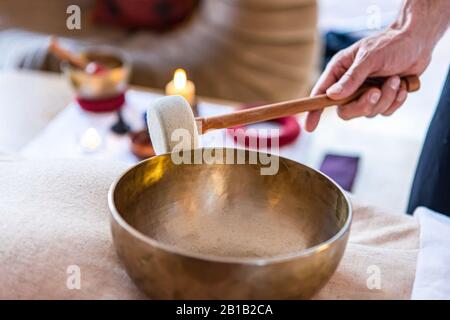 Massaggio terapista che dà un massaggio sonoro con ciotola tibetana. La terapia del suono è usata per fare un massaggio speciale rilassante del corpo e della mente. Vista ravvicinata Foto Stock