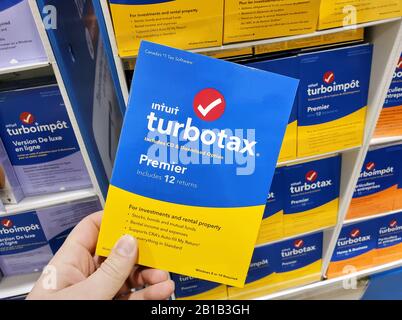 Montreal, Canada - 10 febbraio 2020: Software TurboTax Premier su CD e scatola di licenza in una mano. TurboTax è un pacchetto software per la preparazione delle imposte americano Foto Stock