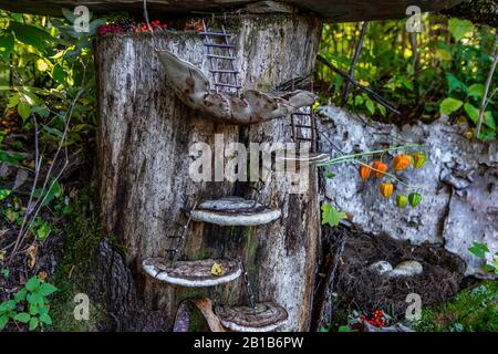 Un primo piano di una mistica e incantevole città delle fate, funghi e scale artigianali decorano il bosco con nido e offerte, copiano lo spazio ai lati Foto Stock