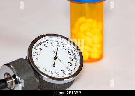 Closeup del manometro della pressione sanguigna con la lettura sistolica normale di 120 mmHg. Medicina di prescrizione flacone con pillole in background Foto Stock