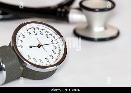 Primo piano del manometro della pressione sanguigna con un valore sistolico elevato di 170 mmHg. Stetoscopio in background Foto Stock