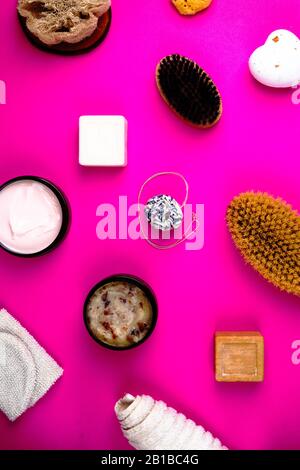 Scrub, lozione, saponi, salvietta di cotone, guanto per la cura del corpo su sfondo rosa. Kit spa eco-compatibile, a disposizione piatta Foto Stock