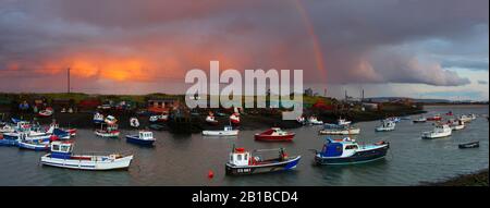 Cielo drammatico e arcobaleno sopra un piccolo porto di pesca a South Gare, Redcar, North Yorkshire, Inghilterra, Regno Unito. Foto Stock