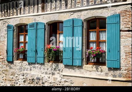 Una vista di finestre blu con copertura decorata con piante di vaso nella città francese di Nerac, Francia sud-occidentale Foto Stock