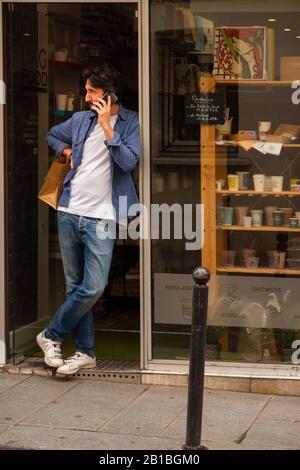 Uomo che parla sul telefono cellulare in panetteria porta Parigi Francia Foto Stock