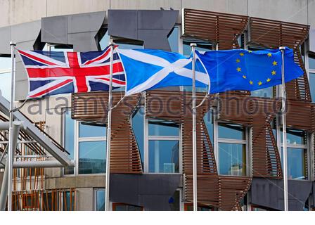 Le bandiere dell'Unione Jack, Saltire e dell'Unione europea al di fuori del parlamento scozzese si sono estese completamente con un vento forte Foto Stock