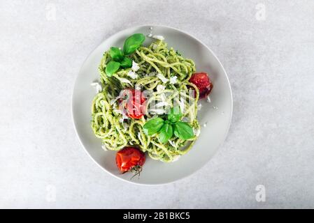Spaghetti alla pasta con salsa al pesto fatta in casa, pomodori arrostiti e foglie di basilico fresco, cibo vegetariano Foto Stock