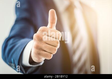 L'uomo d'affari mostra il gesto di segno del pollice in su. Foto Stock