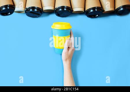 Tazza di caffè di bambù sfondo blu. Una tazza di caffè eco in mano femminile. Foto Stock