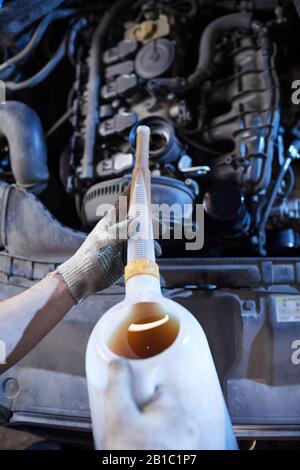 Vista dall'alto sfondo di olio per cambio meccanico di auto non riconoscibile nel motore presso l'officina di riparazione automatica, copia spazio Foto Stock