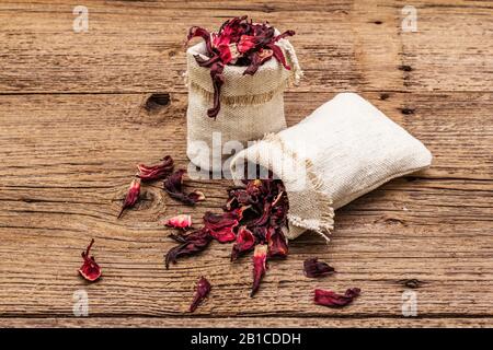 Petali di ibisco secchi. Ingrediente per cucinare tè caldo. Cibo sano e concetto di auto-cura. Vecchi sfondi legno tavole, copia spazio, primo piano Foto Stock