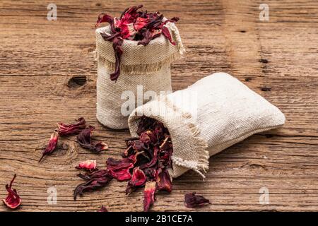 Petali di ibisco secchi. Ingrediente per cucinare tè caldo. Cibo sano e concetto di auto-cura. Vecchi sfondi legno tavole, copia spazio, primo piano Foto Stock