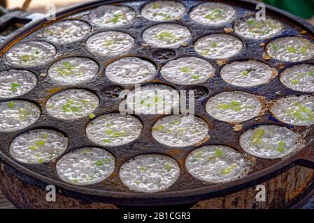 Tailandese tradizionale cibo di strada dessert, Kanom Krok o noce di cocco frittelle di riso. Close-up street food sfondo dalla Tailandia Foto Stock