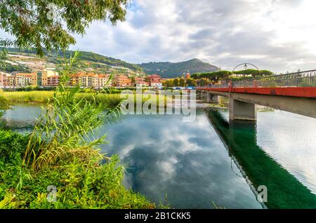 Vista su un ponte che attraversa il fiume Roya, sulla costa della Riviera Mediterranea d'Italia, con la città di Ventimiglia, Italia dall'altra parte. Foto Stock