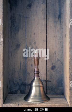 Campanella color bronzo con manico in legno all'interno di una scatola in legno Foto Stock