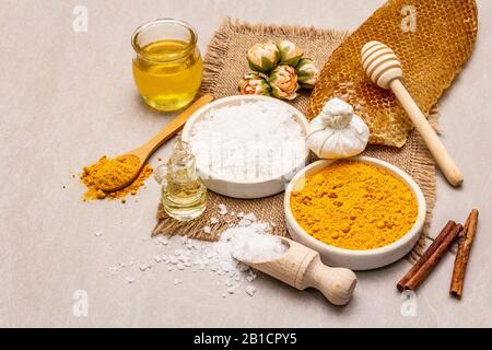 Cura personale con ingredienti naturali. Sano concetto di spa. Curcuma, sale marino, miele, cannella, olio. Pietra sfondo cemento, primo piano Foto Stock