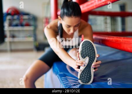 Donna sportiva che allunga le gambe per riscaldarsi prima di allenarsi in palestra. Concetto di sport Foto Stock