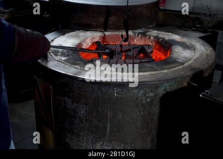 Processo di rinvenimento in fabbrica di coltelli. Forno, bagno d'olio e scarico Foto Stock