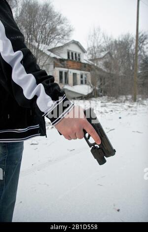 Uomo che tiene la pistola Glock sulla strada coperta di neve a Detroit, Michigan, Stati Uniti Foto Stock