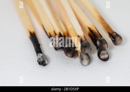 diversi fiammiferi bruciati giacciono fianco a fianco su una base bianca Foto Stock