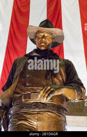 Una statua in bronzo di John Wayne, famoso attore americano, vestito da cowboy, si trova all'aeroporto John Wayne, Orange County, a Santa Ana, California. Foto Stock