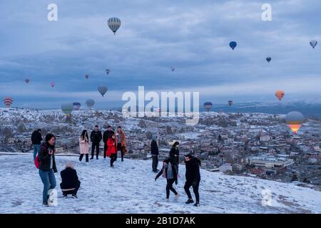 Cappadocia in inverno coperto di neve, turisti e mongolfiera decollo vicino a Göreme Foto Stock