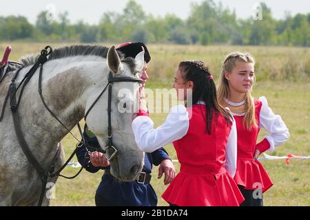 Samara , Russia - 17 agosto 2019: Giovane Cossack e ragazza Cossack in costumi nazionali in piedi accanto al cavallo. La ragazza dice addio al Cossac Foto Stock