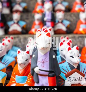 Piccole statue colorate di volpe al santuario di Fushimi Inari. Si ritiene che le volpi siano messaggeri di dio. Kyoto, Giappone Foto Stock