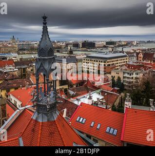 Budapest, Ungheria - Vecchia torre di ferro e tetti rossi del quartiere del Castello con il Ponte delle catene Szechenyi, la Basilica di Santo Stefano e le nuvole scure in inverno ti Foto Stock