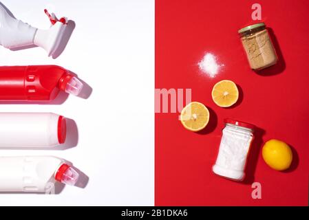 Bicarbonato di sodio, limone e polvere di senape contro prodotti chimici domestici su sfondo rosso. Vista dall'alto. Spazio di copia. Disposizione piatta. Pulizia della casa efficace e sicura. Foto Stock