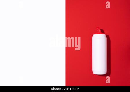 Flacone di plastica bianca con detersivo in polvere o detergente su sfondo rosso. Spazio di copia. Vista dall'alto. Disposizione piatta. Concetto di prodotti chimici domestici. Foto Stock