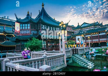 Un turista che indossa una maschera facciale prende un selfie di fronte alla teahouse di Huxinting nello Yuyuan di Shanghai. Foto Stock