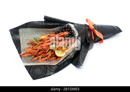 Regalo originale sotto forma di bouquet di gamberi bolliti, fette di limone e olive nere su sfondo bianco. Foto Stock