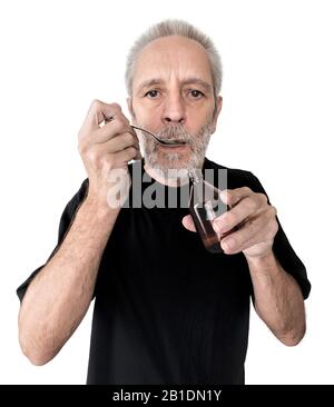 Un uomo maturo beve un cucchiaio di sciroppo di tosse per curare la sua mal di gola e la bronchite. Isolato su sfondo bianco Foto Stock